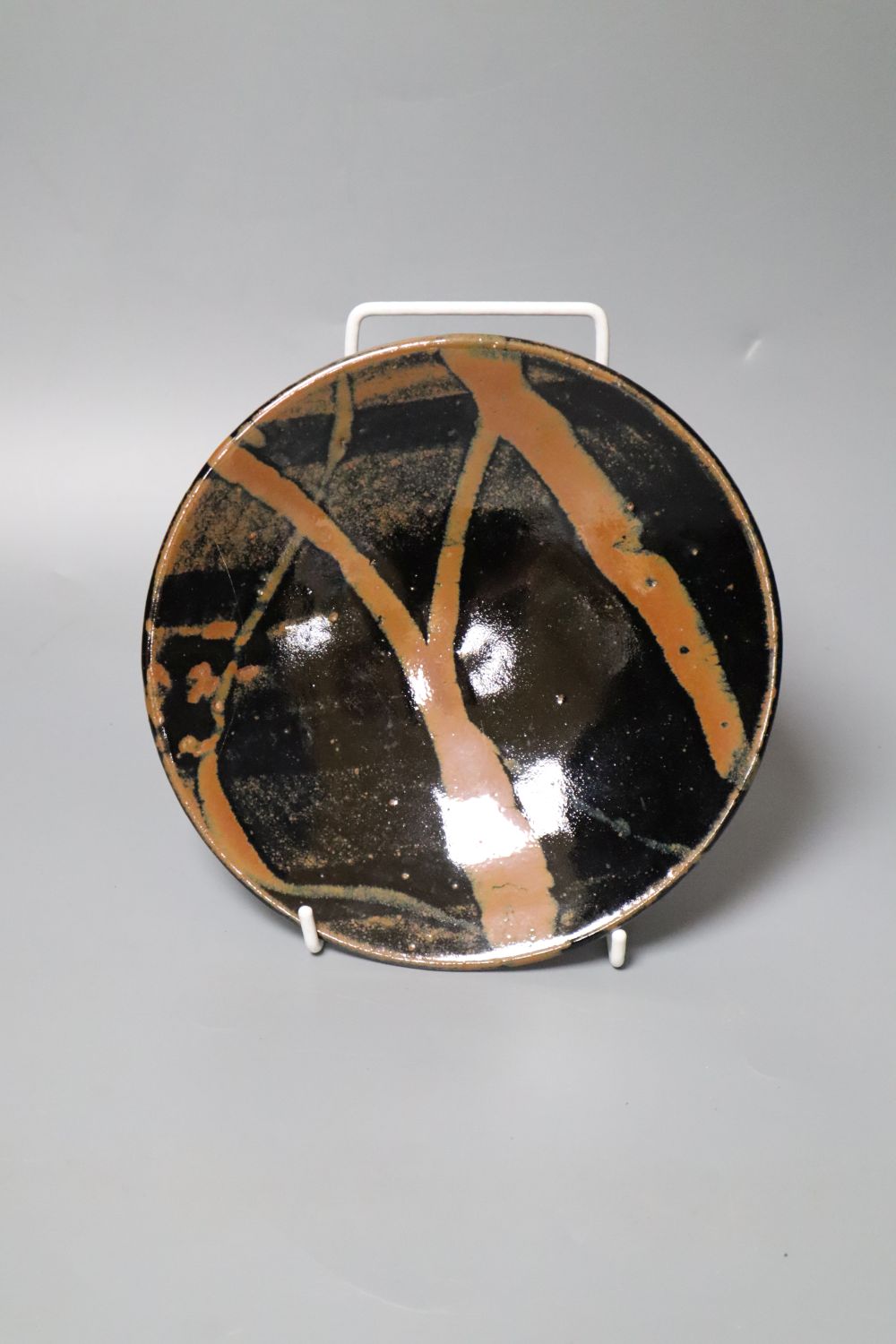 Attributed to Shoji Hamada (1894-1978). A shallow circular persimmon-glazed dish, diameter 18cm (damage)